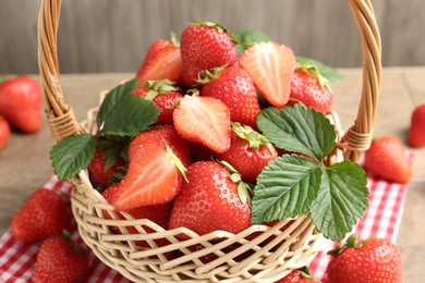 Photo of Delicious ripe strawberries in wicker basket on table, closeup