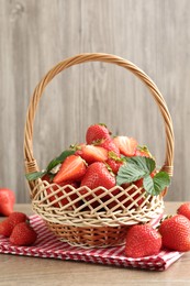 Photo of Delicious ripe strawberries in wicker basket on wooden table