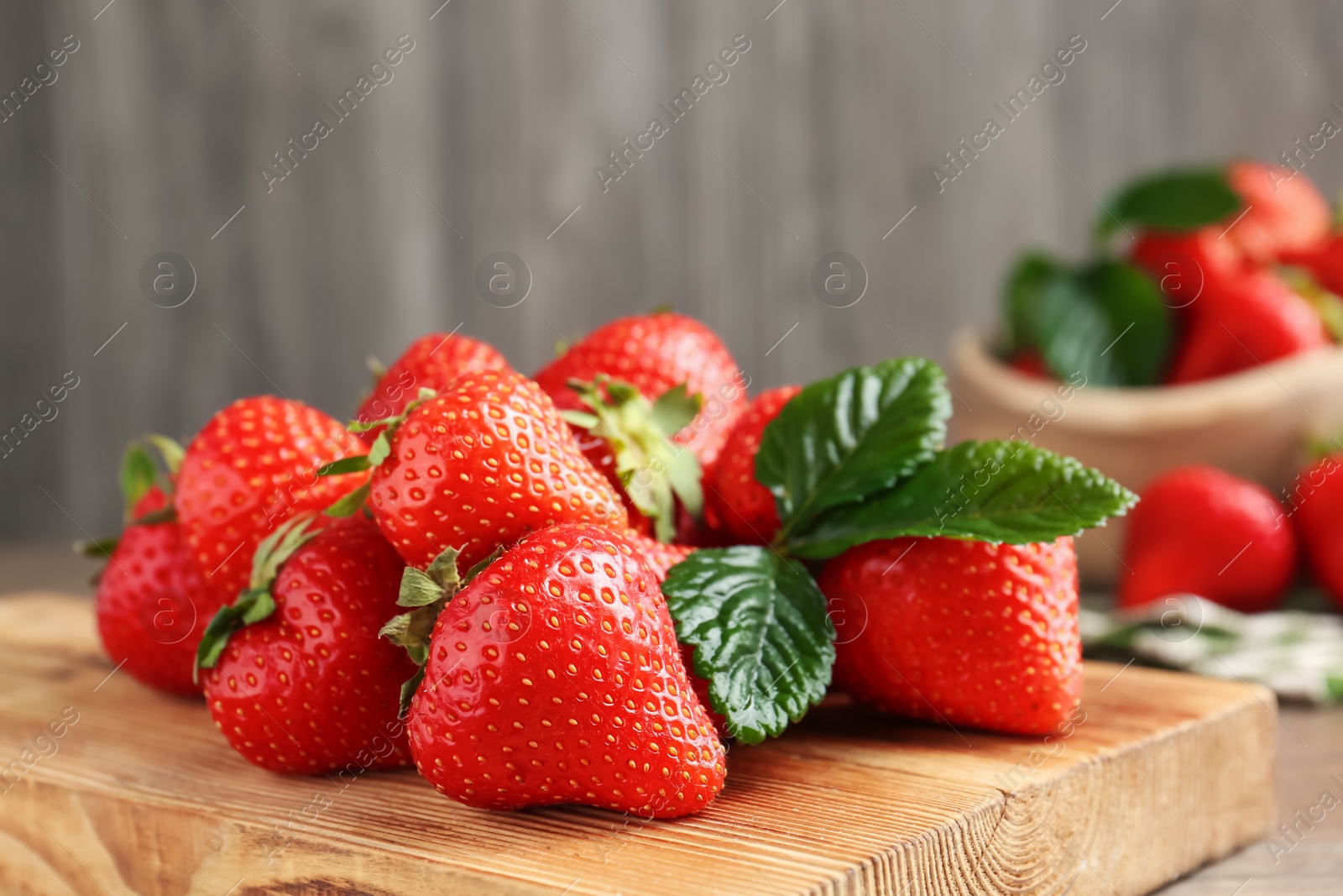 Delicious ripe strawberries and green leaves on table, closeup Photo of Delicious ripe strawberries and green leaves on table, closeup