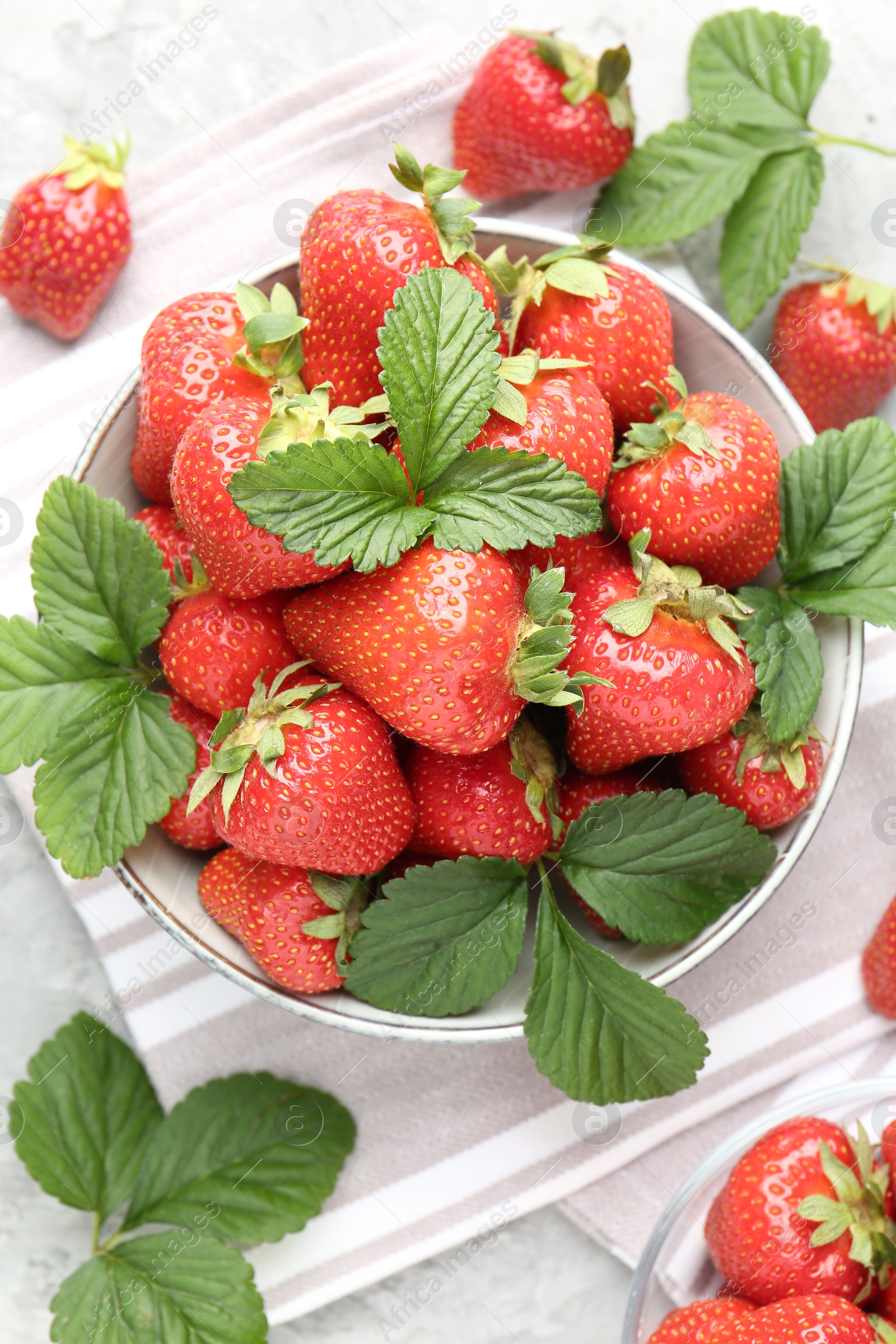 Photo of Delicious ripe strawberries and green leaves on table, flat lay