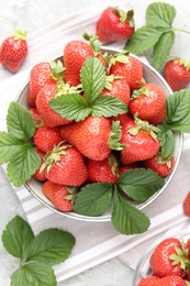 Photo of Delicious ripe strawberries and green leaves on table, flat lay