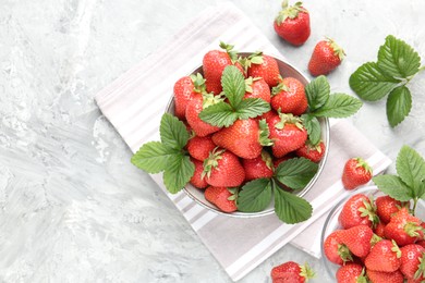 Photo of Delicious ripe strawberries and green leaves on grey table, flat lay. Space for text