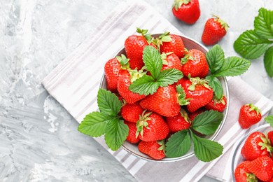 Photo of Delicious ripe strawberries and green leaves on grey table, flat lay. Space for text