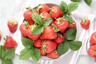Photo of Delicious ripe strawberries and green leaves on table, flat lay