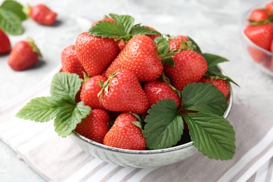 Photo of Delicious ripe strawberries and green leaves on table, closeup