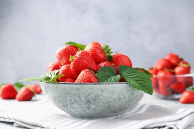 Photo of Delicious ripe strawberries and green leaves on table, closeup