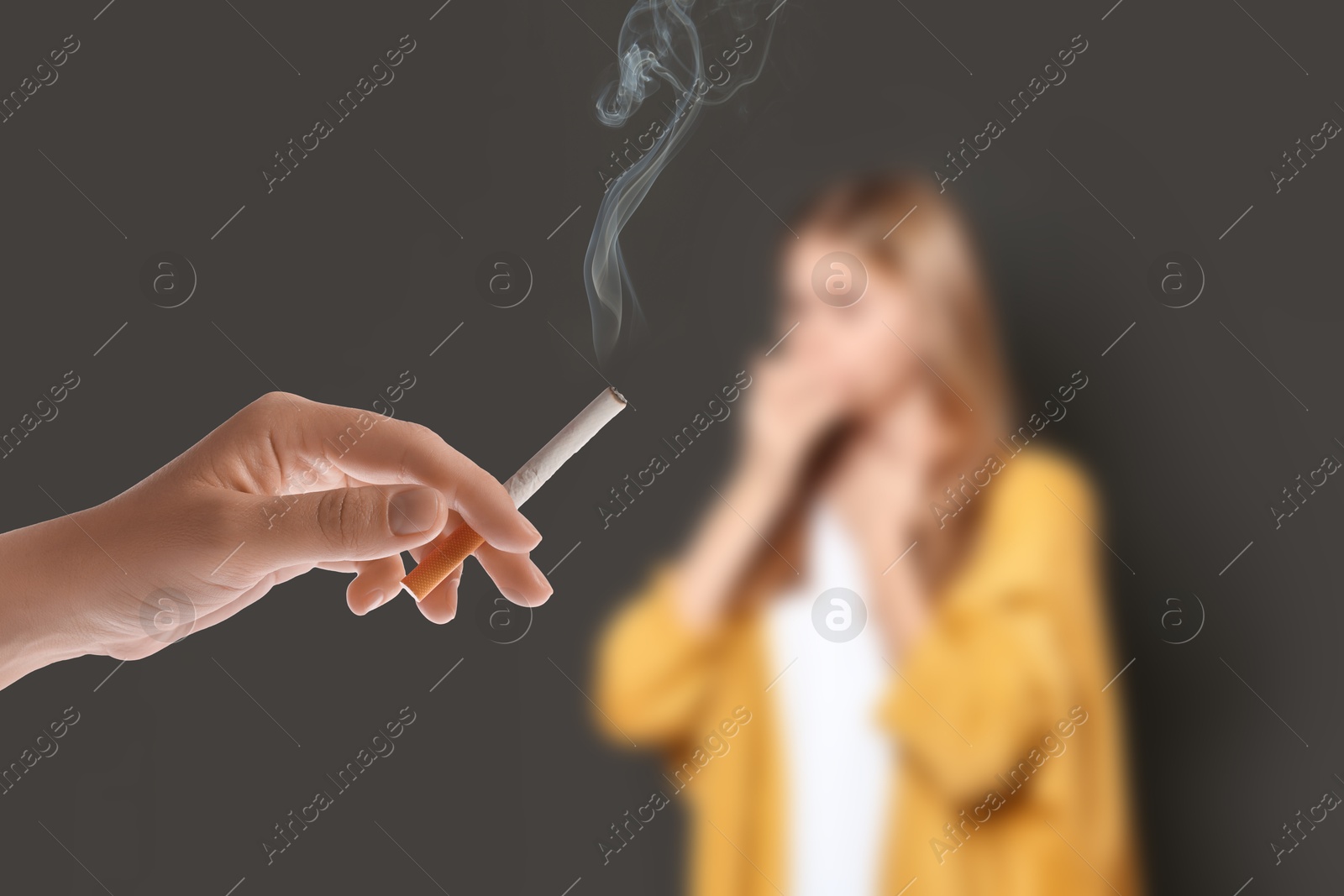Passive smoking. Girl coughing because of woman smoking nearby on grey background. Selective focus Image of Passive smoking. Girl coughing because of woman smoking nearby on grey background. Selective focus