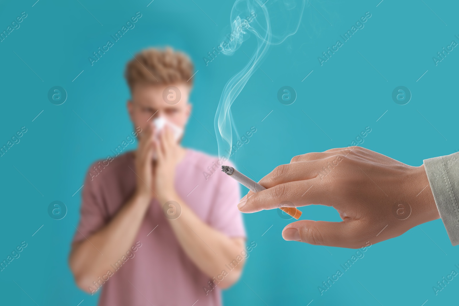 Passive smoking. Man covering his nose with tissue because of woman smoking nearby on light blue background. Selective focus Image of Passive smoking. Man covering his nose with tissue because of woman smoking nearby on light blue background. Selective focus