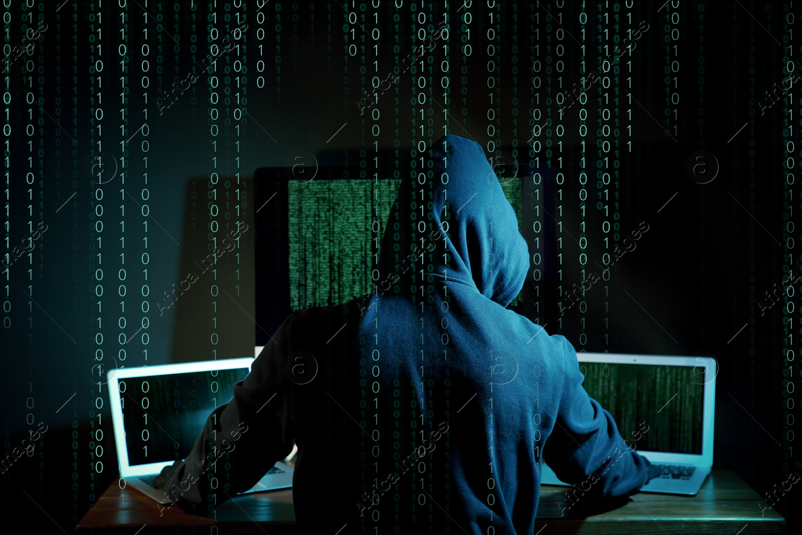Cyber attack. Hacker working on computers in dark room. Binary code around him Image of Cyber attack. Hacker working on computers in dark room. Binary code around him