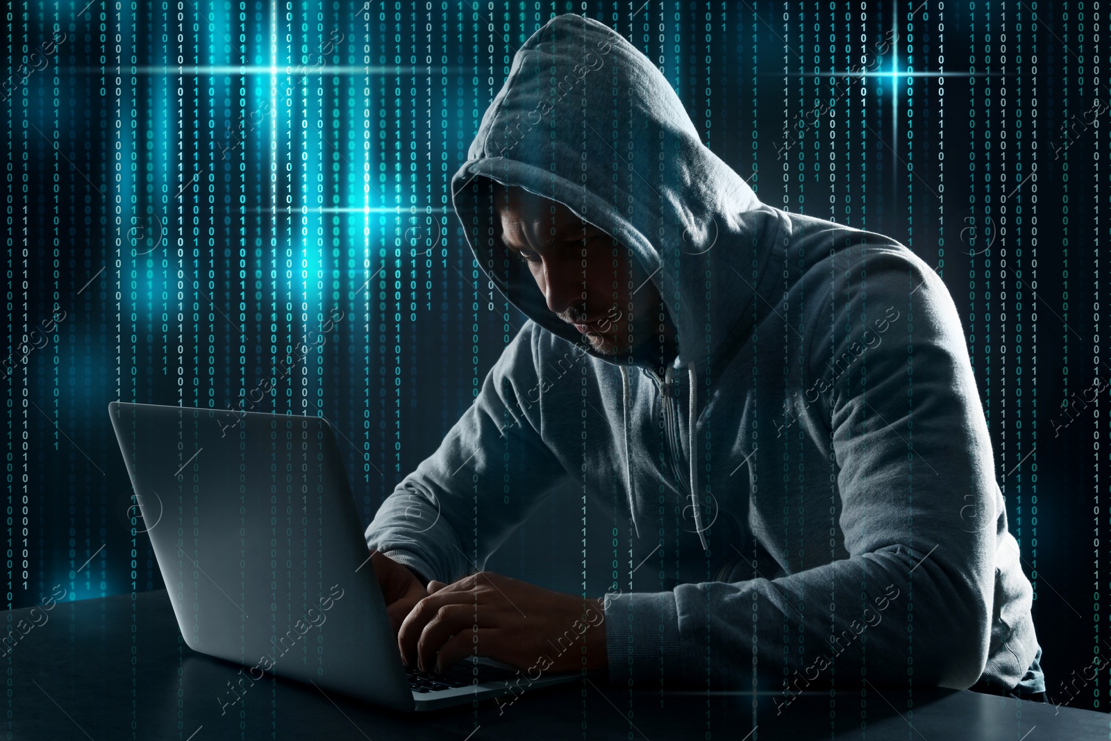 Cyber attack. Hacker working with laptop at table. Binary code around him Image of Cyber attack. Hacker working with laptop at table. Binary code around him