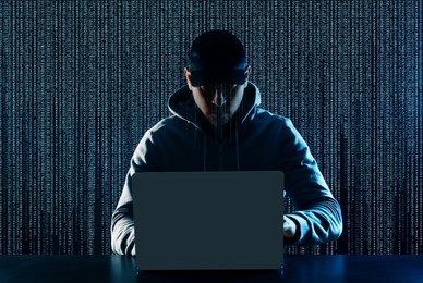 Image of Cyber attack. Hacker working on laptop at table. Digital code behind him