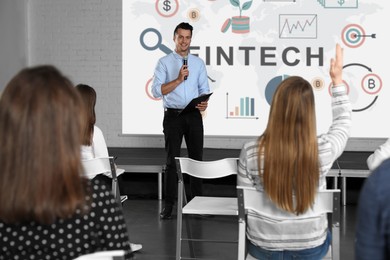 Image of Business trainer giving lecture using video projector in conference room. Fintech word and illustrations on projection screen