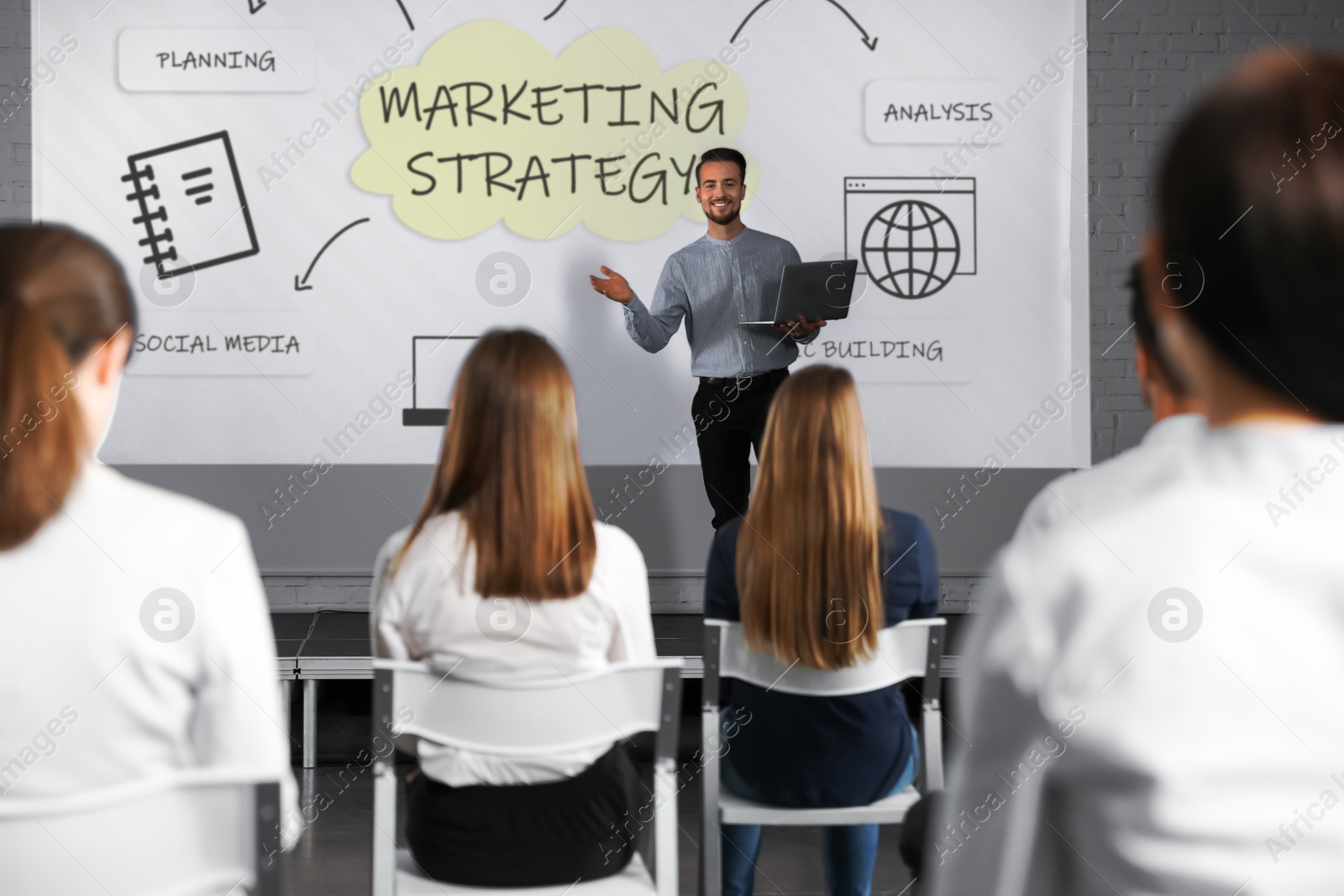Business trainer giving lecture using video projector in conference room. Marketing strategy scheme with illustrations on projection screen Image of Business trainer giving lecture using video projector in conference room. Marketing strategy scheme with illustrations on projection screen