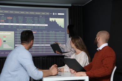 Image of Business trainer giving lecture using video projector in conference room. Graphs and data on projection screen
