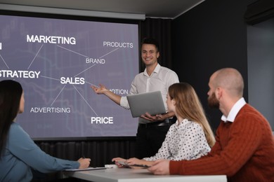 Image of Business trainer giving lecture using video projector in conference room. Scheme on projection screen
