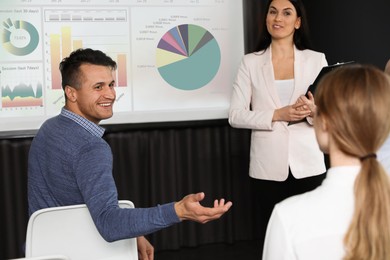 Image of Business trainer giving lecture using video projector in conference room. Graphs on projection screen