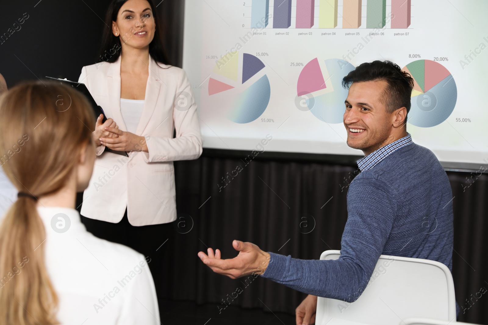 Business trainer giving lecture using video projector in conference room. Graphs on projection screen Image of Business trainer giving lecture using video projector in conference room. Graphs on projection screen