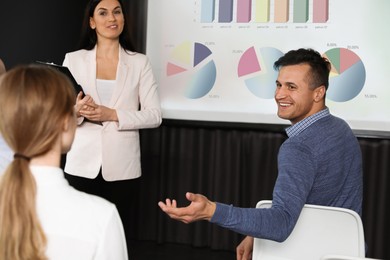 Image of Business trainer giving lecture using video projector in conference room. Graphs on projection screen