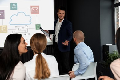 Image of Business trainer giving lecture using video projector in conference room. Scheme with illustrations on projection screen