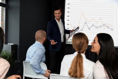 Image of Business trainer giving lecture using video projector in conference room. Graph on projection screen