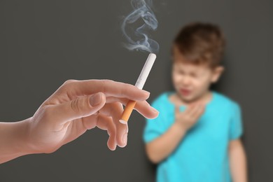 Image of Passive smoking. Little boy coughing because of man smoking nearby on grey background. Selective focus