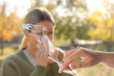 Image of Passive smoking. Woman covering her nose with tissue because of girl smoking nearby outdoors. Selective focus