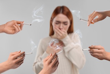 Image of Passive smoking. Woman coughing because of people smoking nearby on light grey background. Selective focus