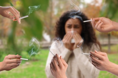 Image of Passive smoking. Woman covering her nose with tissue because of people smoking nearby outdoors. Selective focus