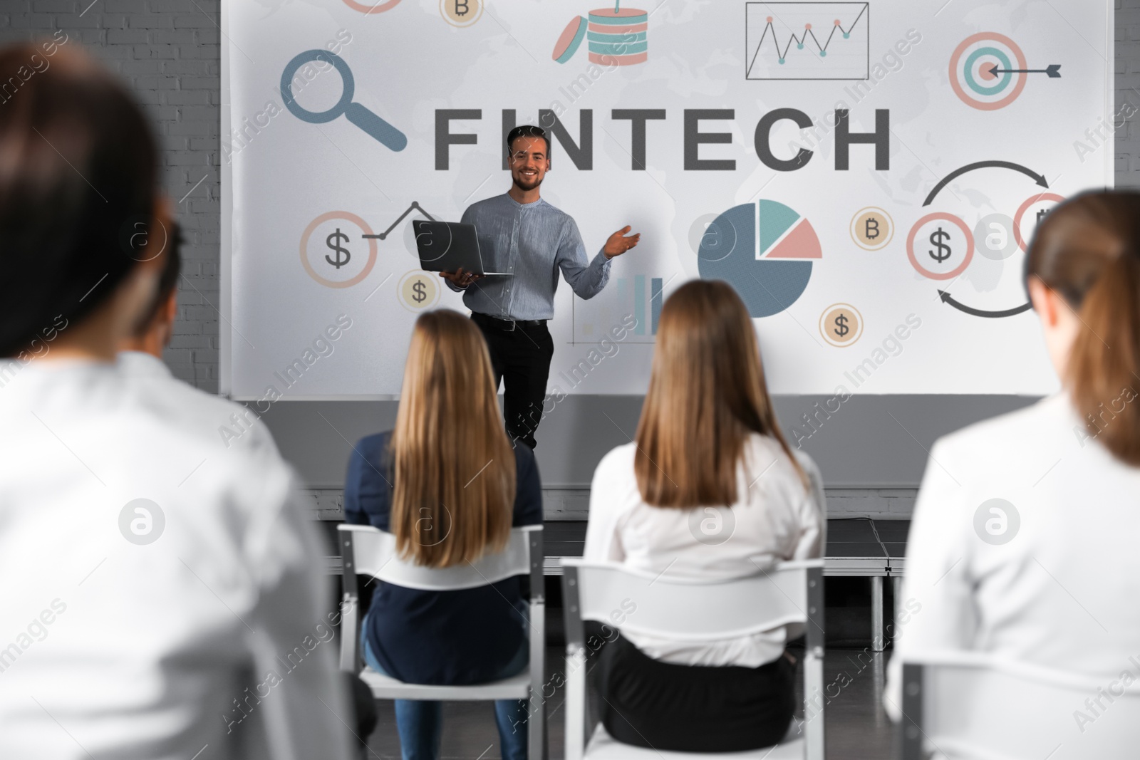 Business trainer giving lecture using video projector in conference room. Fintech word and illustrations on projection screen Image of Business trainer giving lecture using video projector in conference room. Fintech word and illustrations on projection screen