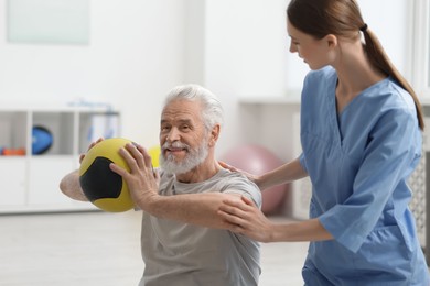 Photo of Doctor and patient exercising with medicine ball in clinic, space for text
