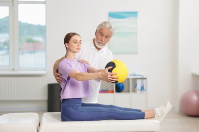 Photo of Doctor and patient exercising with medicine ball in clinic