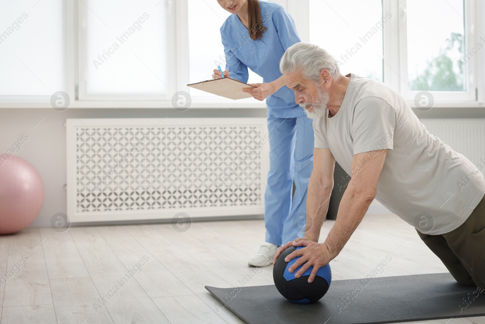 Doctor and patient exercising with medicine ball in clinic, space for text Photo of Doctor and patient exercising with medicine ball in clinic, space for text