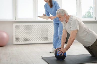 Photo of Doctor and patient exercising with medicine ball in clinic, space for text