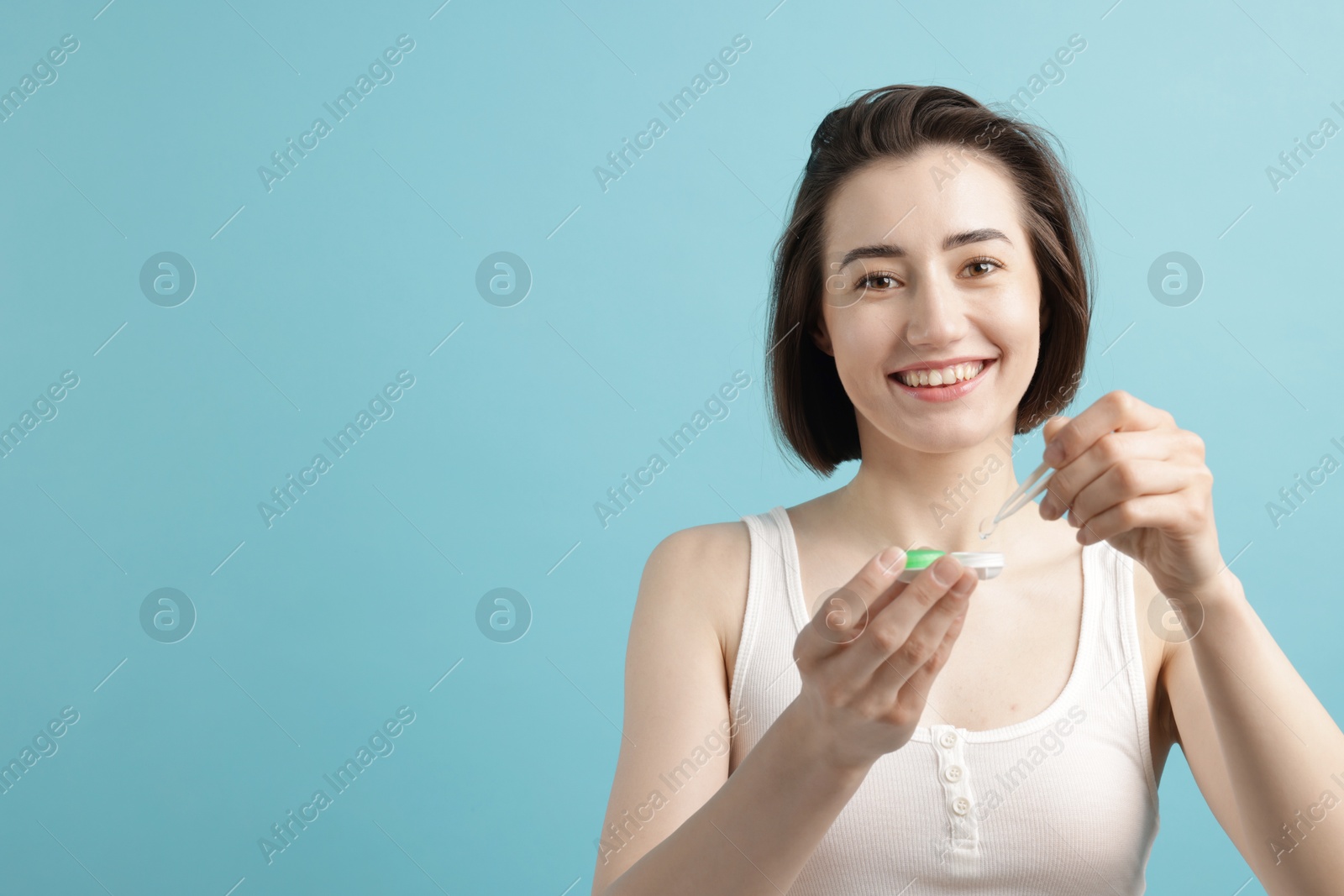 Woman taking contact lens out of case on light blue background. Space for text Photo of Woman taking contact lens out of case on light blue background. Space for text