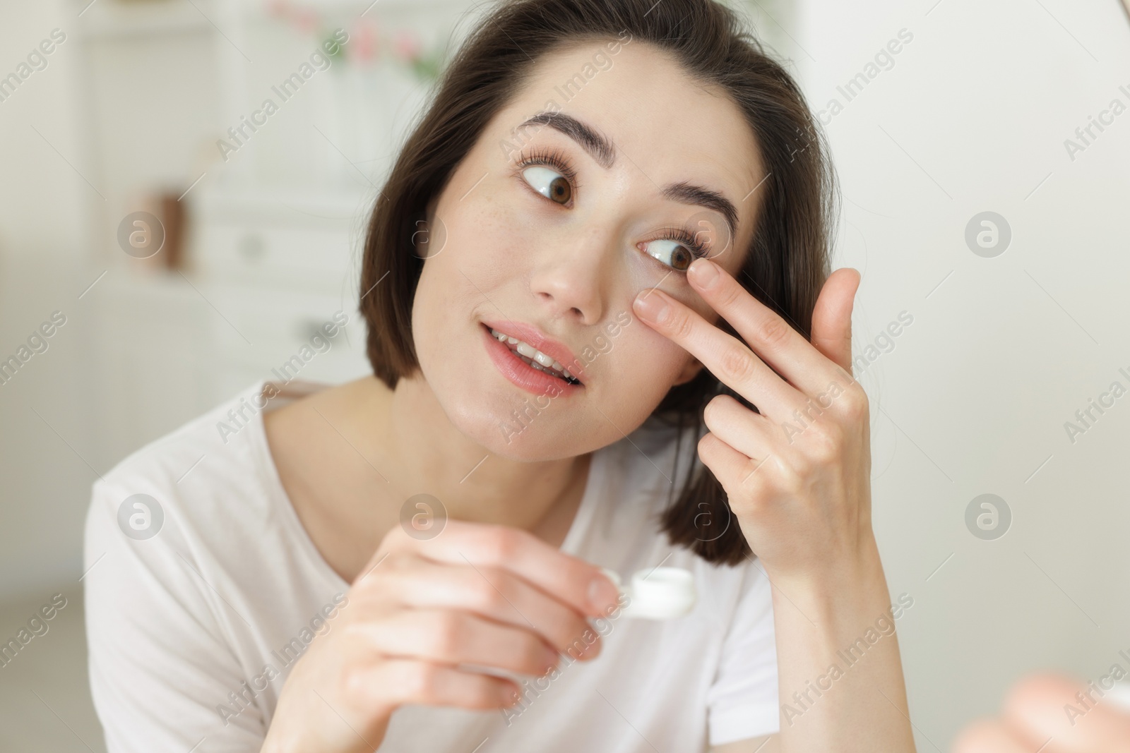 Beautiful woman putting in contact lens indoors Photo of Beautiful woman putting in contact lens indoors