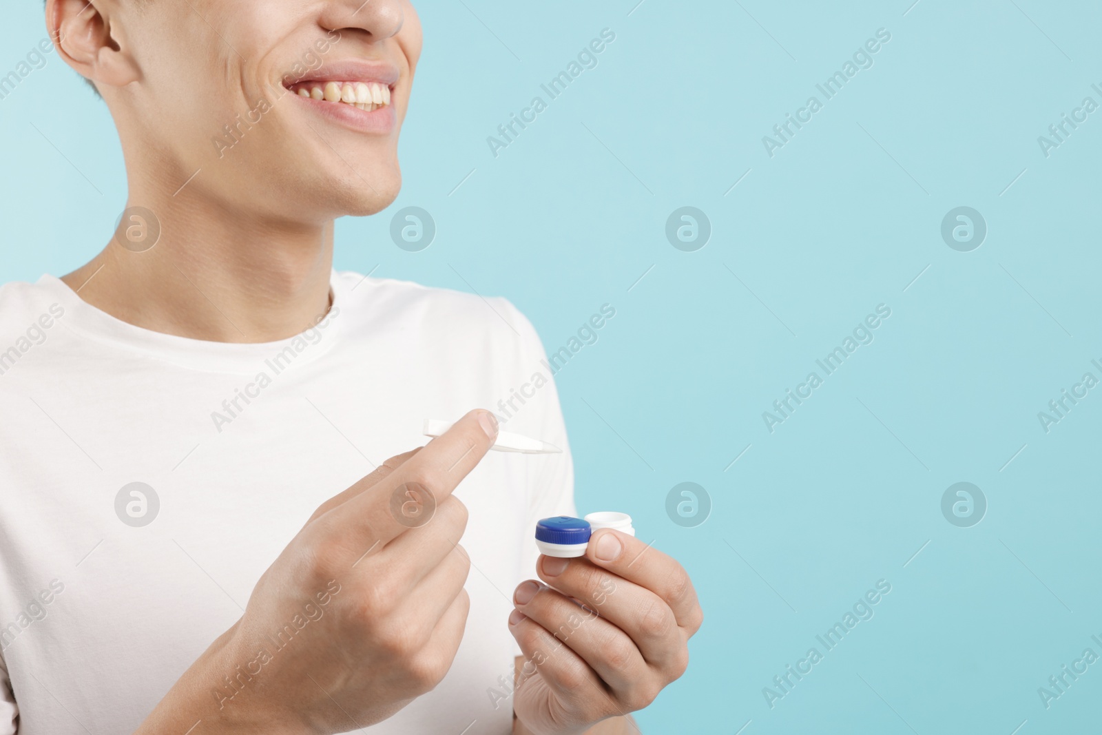 Man with contact lens and case on light blue background, closeup. Space for text Photo of Man with contact lens and case on light blue background, closeup. Space for text