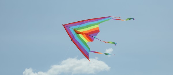 Photo of Colorful kite flying in blue sky, low angle view