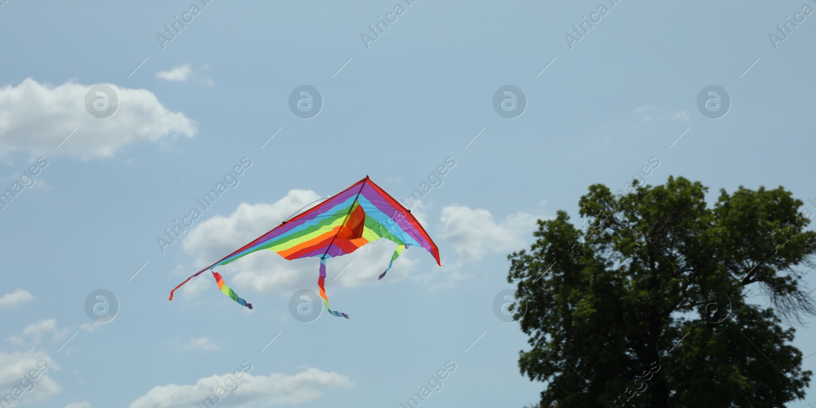 Colorful kite flying in blue sky, low angle view Photo of Colorful kite flying in blue sky, low angle view