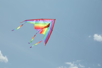 Photo of Colorful kite flying in blue sky, low angle view. Space for text