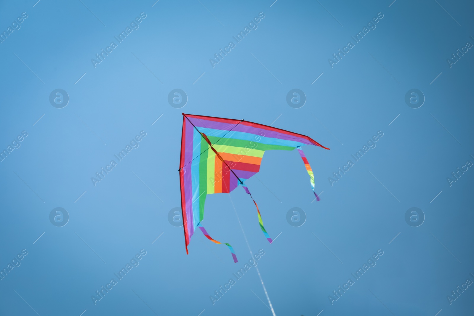 Colorful kite flying in blue sky, low angle view Photo of Colorful kite flying in blue sky, low angle view