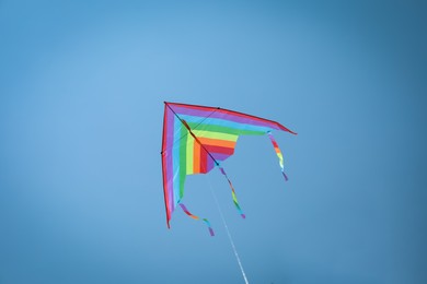 Photo of Colorful kite flying in blue sky, low angle view