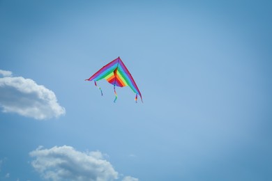 Photo of Colorful kite flying in blue sky, low angle view. Space for text