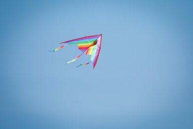 Photo of Colorful kite flying in blue sky, low angle view. Space for text