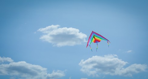 Photo of Colorful kite flying in blue sky, low angle view. Space for text