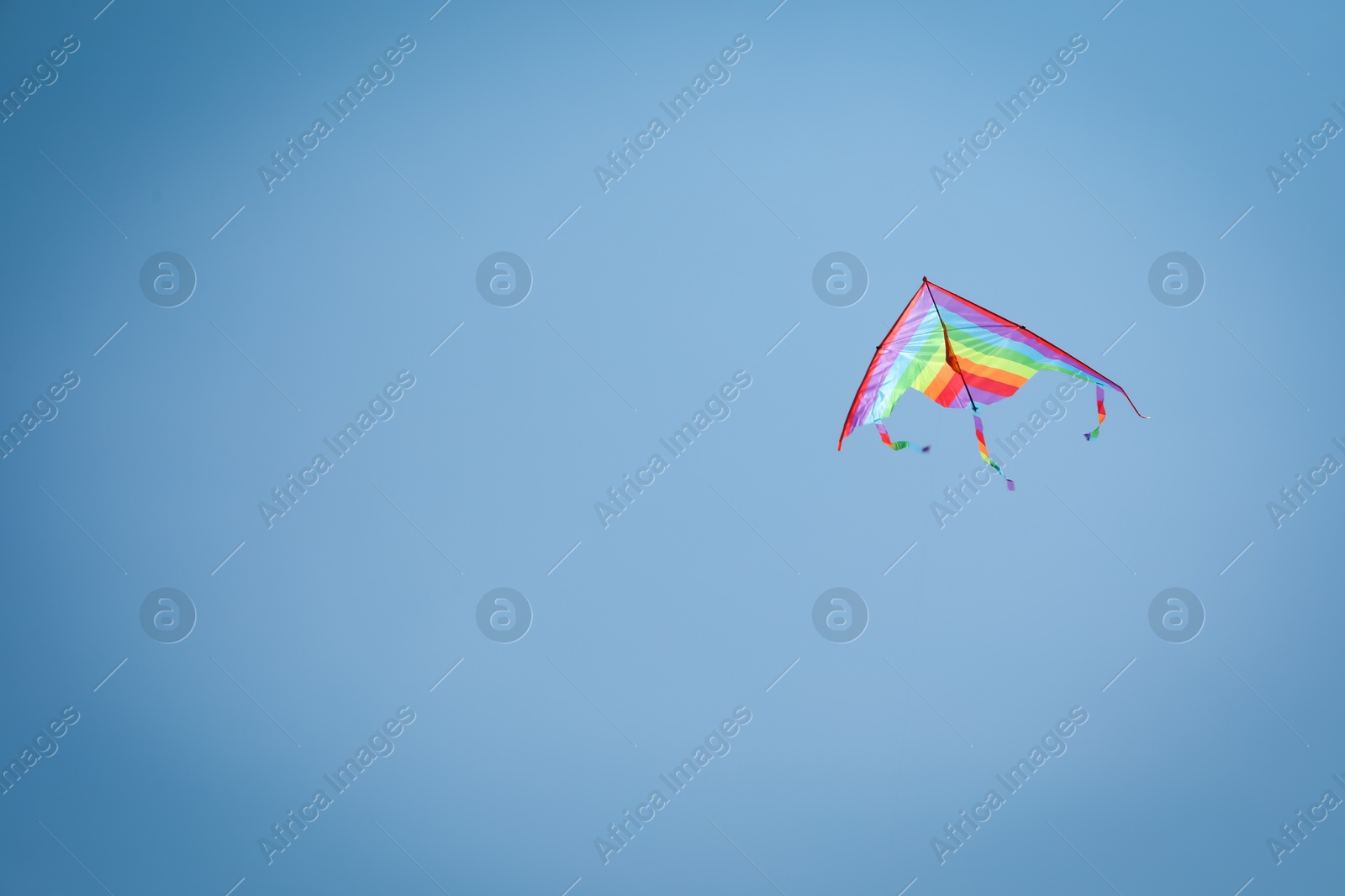 Colorful kite flying in blue sky, low angle view. Space for text Photo of Colorful kite flying in blue sky, low angle view. Space for text