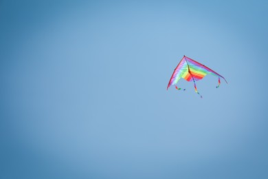 Photo of Colorful kite flying in blue sky, low angle view. Space for text