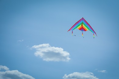 Photo of Colorful kite flying in blue sky, low angle view. Space for text