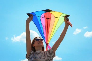 Photo of Woman with colorful kite under blue sky, low angle view