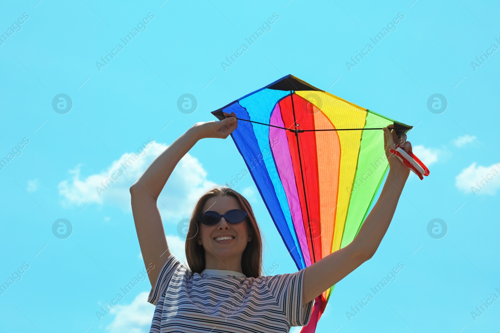 Woman with colorful kite under blue sky, low angle view Photo of Woman with colorful kite under blue sky, low angle view