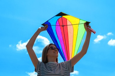 Photo of Woman with colorful kite under blue sky, low angle view